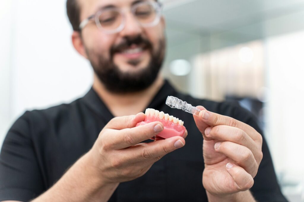 Dentist showing clear aligners on artificial human jaw presenting innovative teeth correction